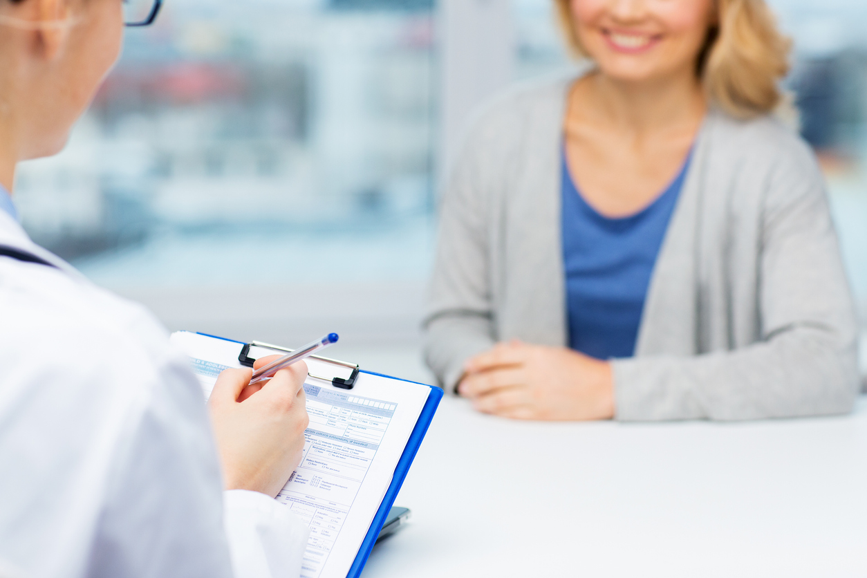 Woman talking to a doctor. The doctor is holding a clipboard.