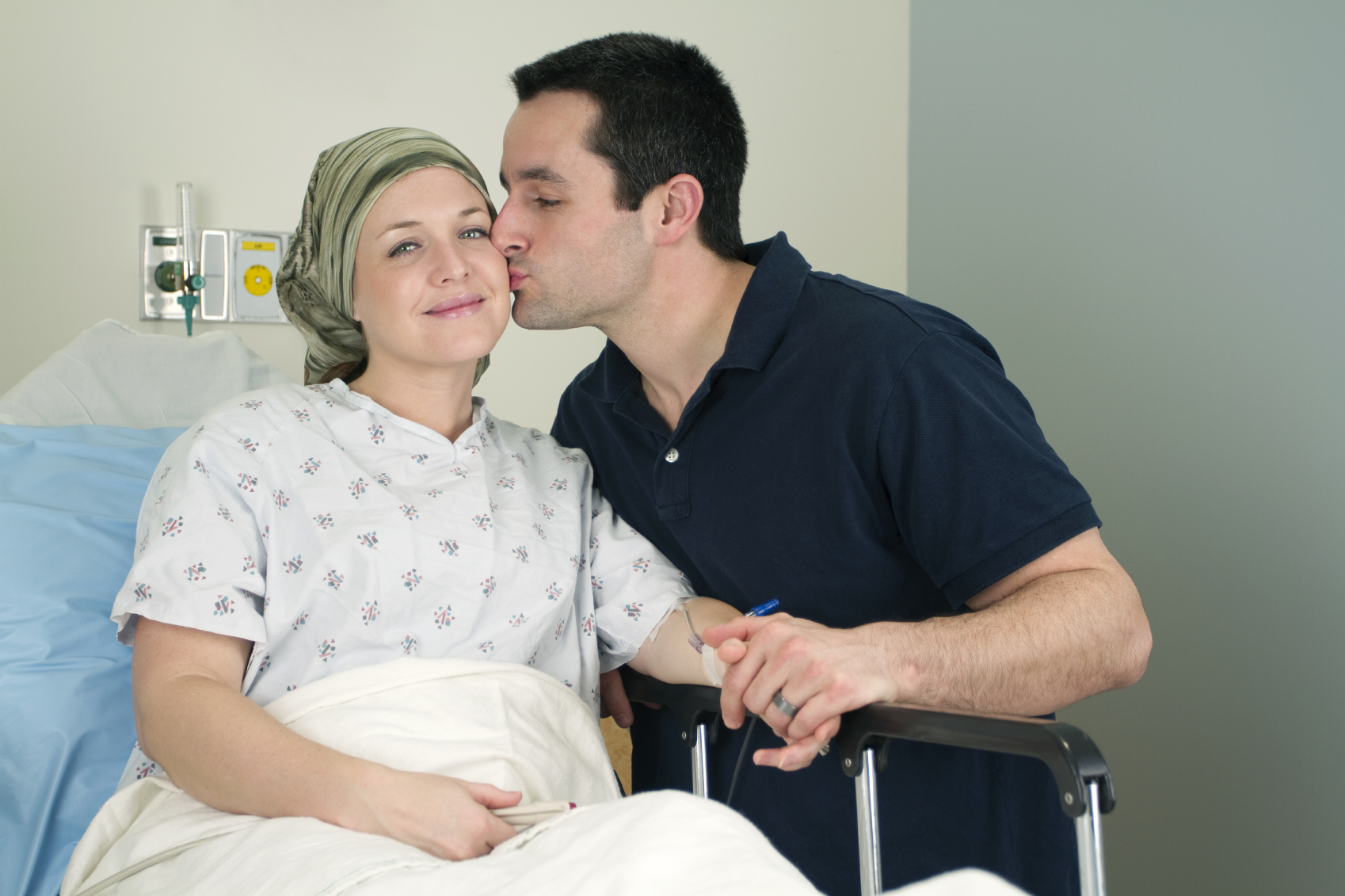 Woman in a hospital bed getting kissed by her husband