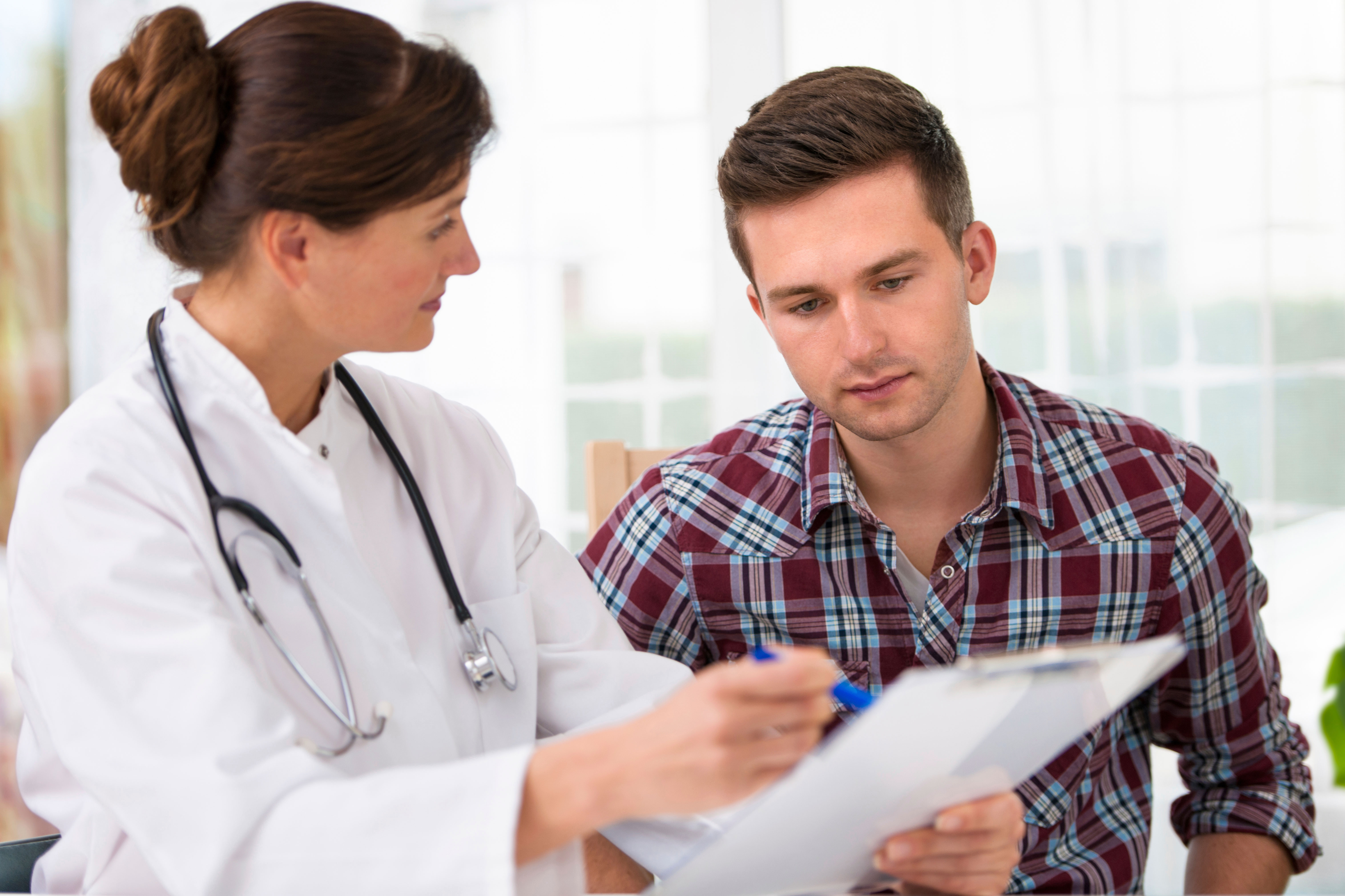 Female doctor explaining something to a young male patient