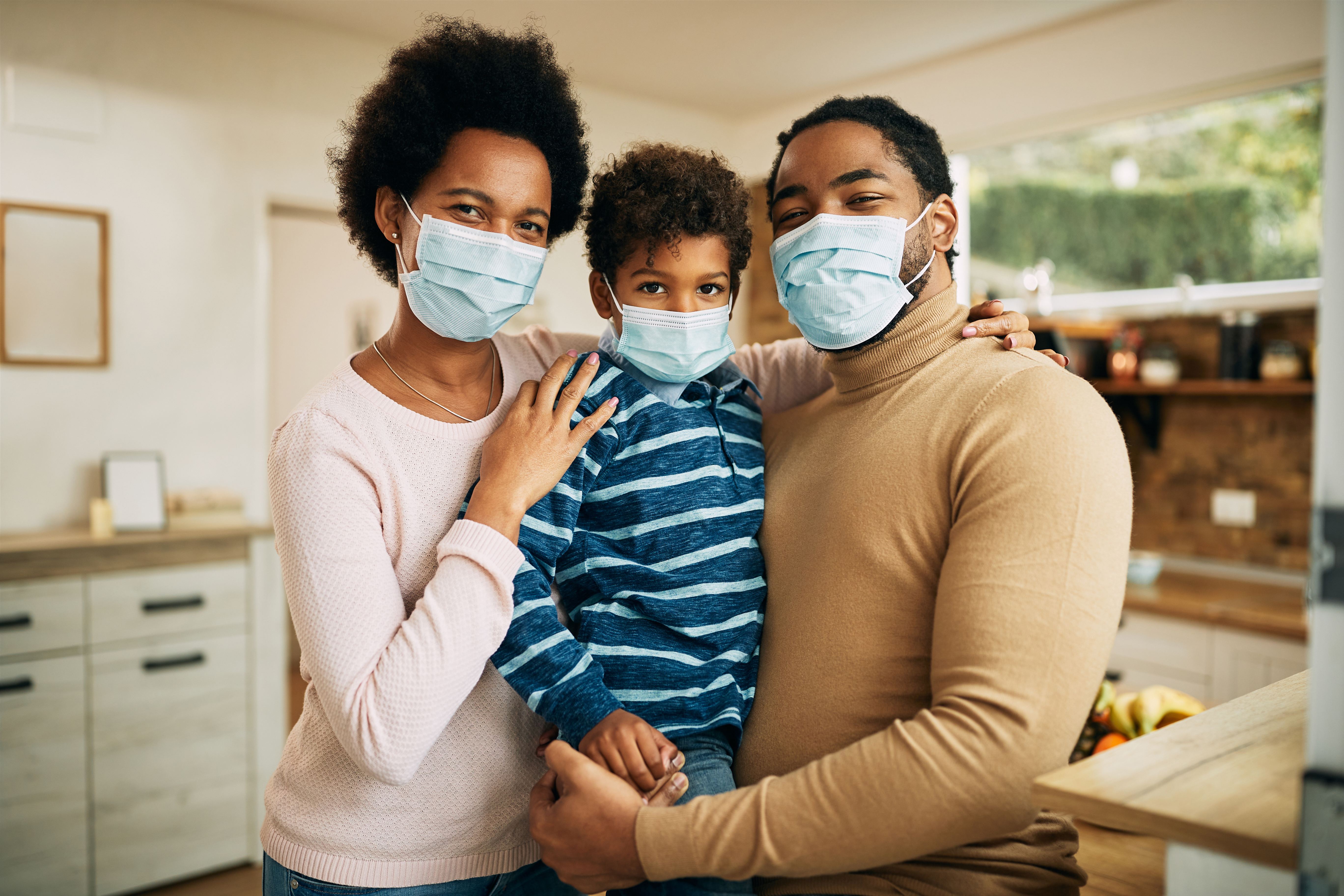 black mother and father with their young son wearing masks at home