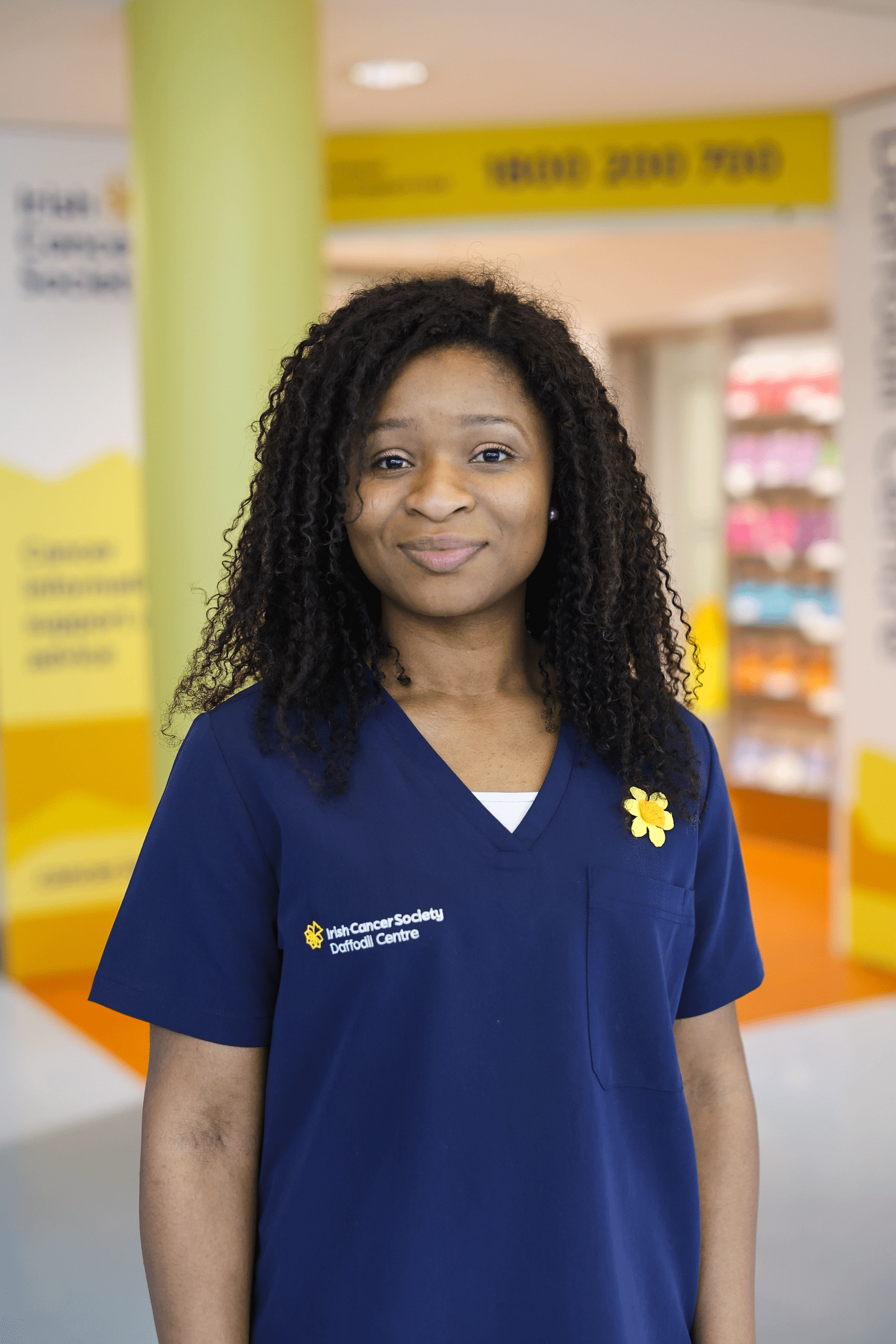 A Daffodil Centre nurse smiles to camera wearing a navy uniform 