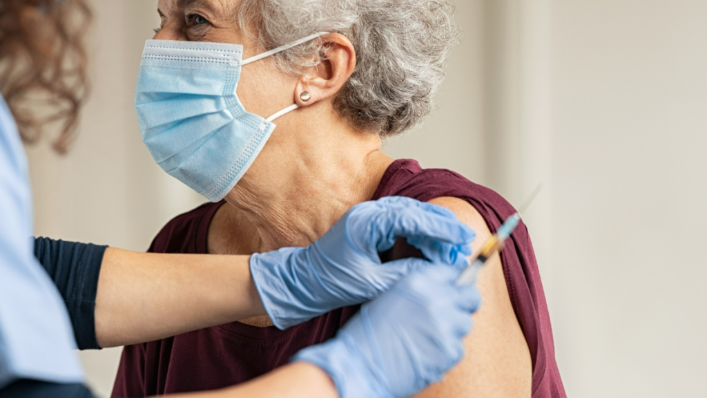 older white woman with short hair getting covid shot from young woman doctor