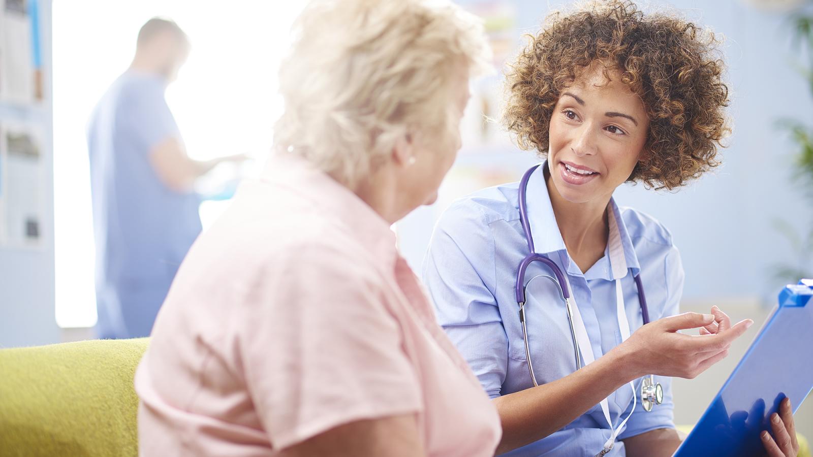 Medical doctor or nurse talking to an older woman patient